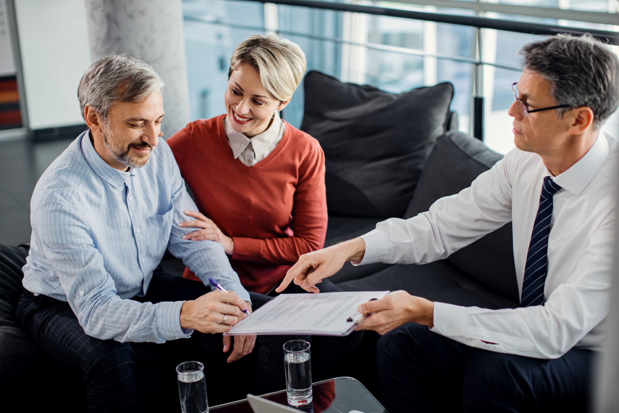 Couple signant un contrat d'assurance emprunteur avec un conseiller en patrimoine