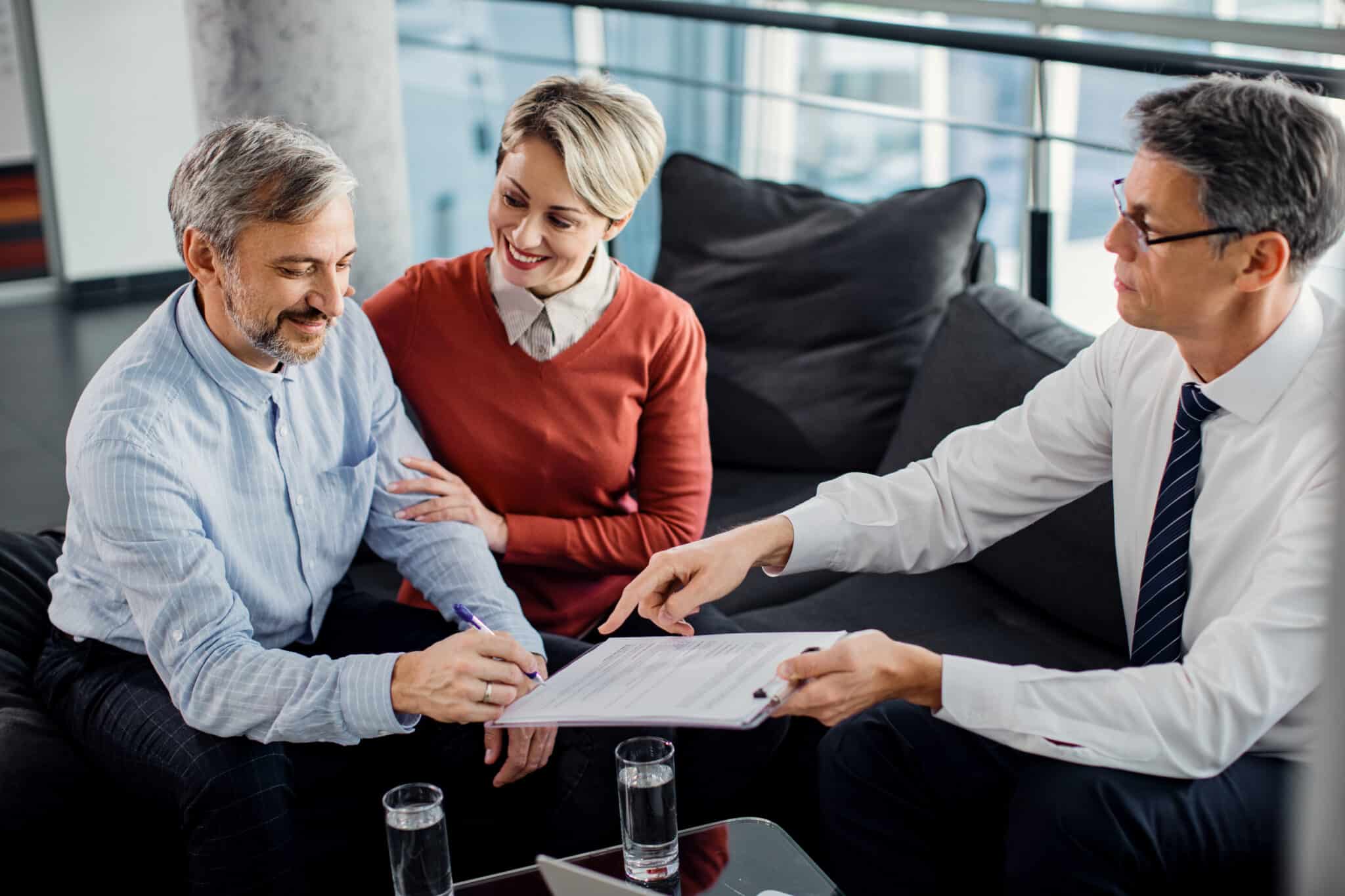Couple signant un contrat d'assurance emprunteur avec un conseiller en patrimoine